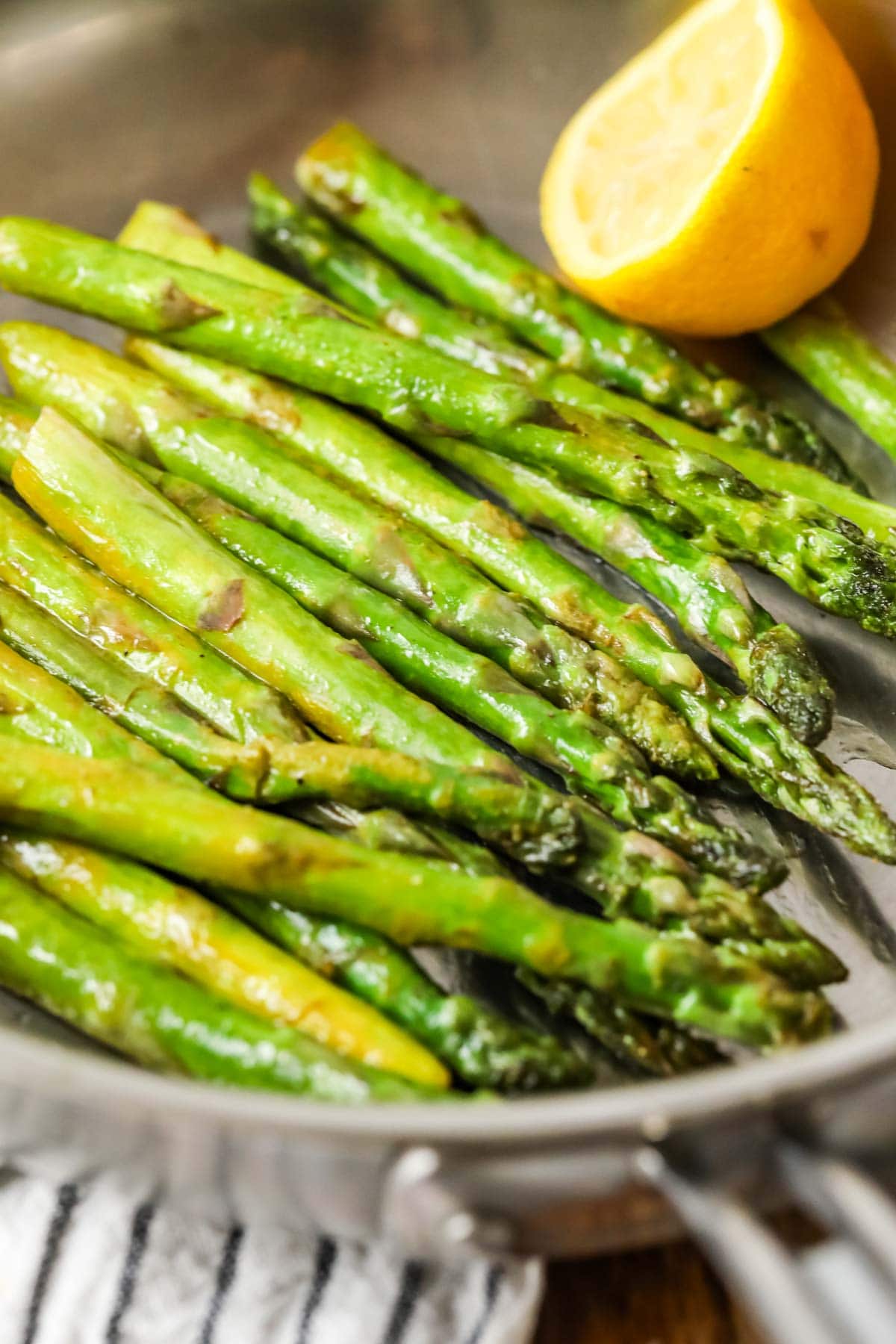 Asparagus spears in a saucepan after being sautéed with lemon and butter.