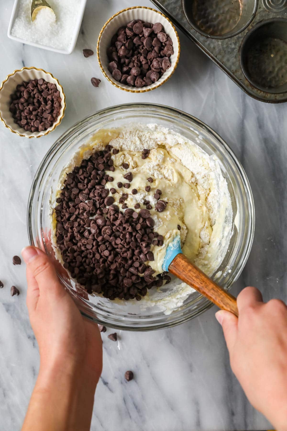 Overhead view of a bowl of muffin batter with chocolate chips being folded in.