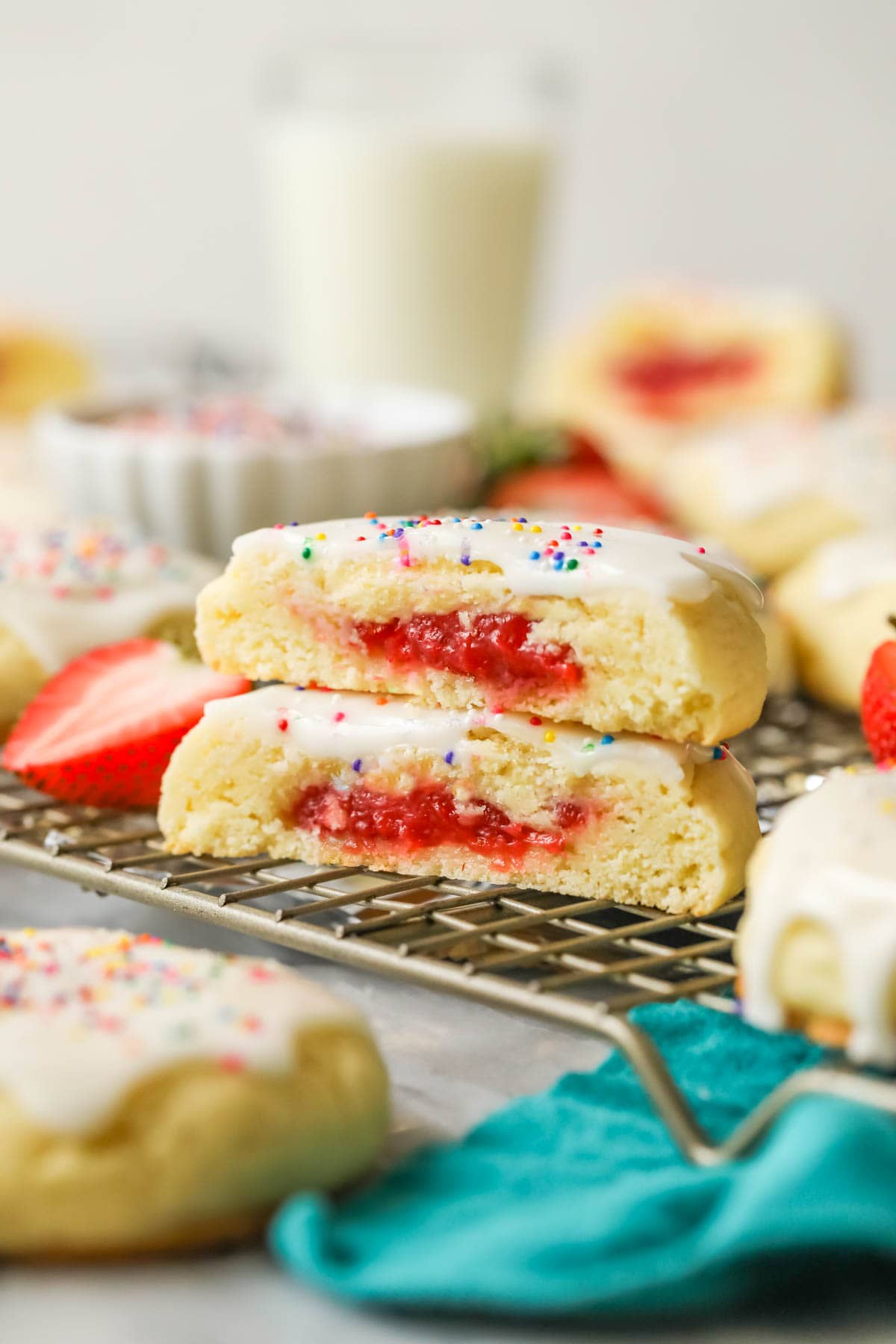 Two stacked halves of a cookie that has been stuffed with strawberry jam and topped with vanilla glaze.