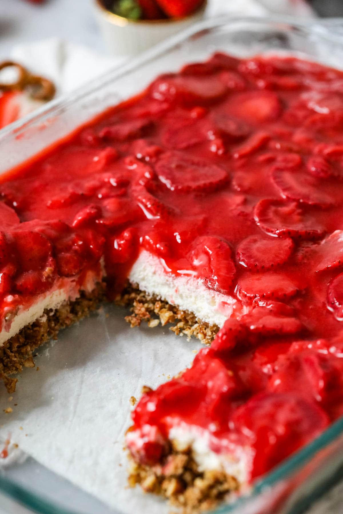 Slices missing from a layered strawberry, pretzel, and cream cheese dessert.