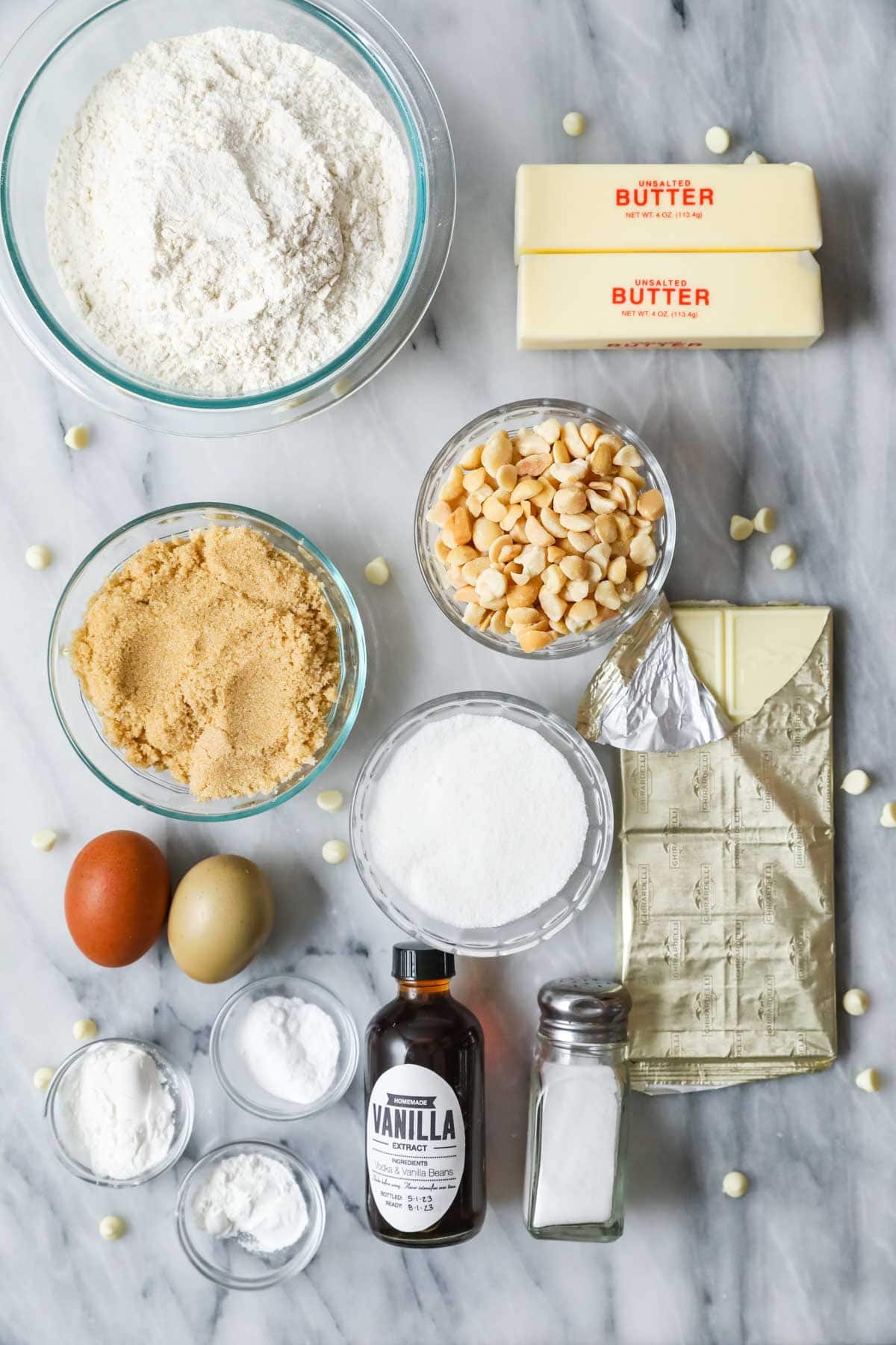 Overhead view of ingredients including macadamia nuts, white chocolate, brown sugar, and more.