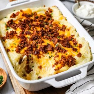 Dish of loaded mashed potato casserole with one serving missing.