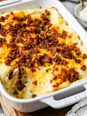 Dish of loaded mashed potato casserole with one serving missing.