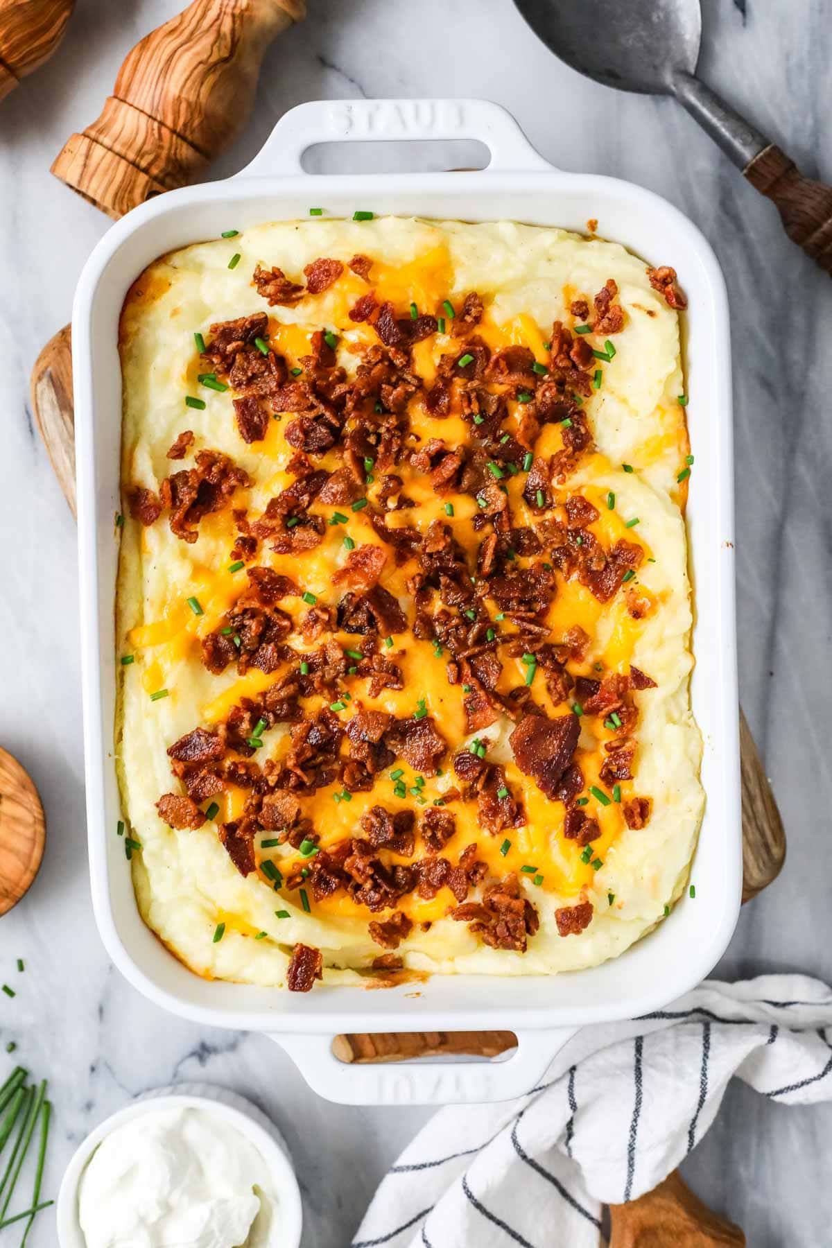 Overhead view of a casserole made with mashed potatoes, cheese, bacon, and chives.