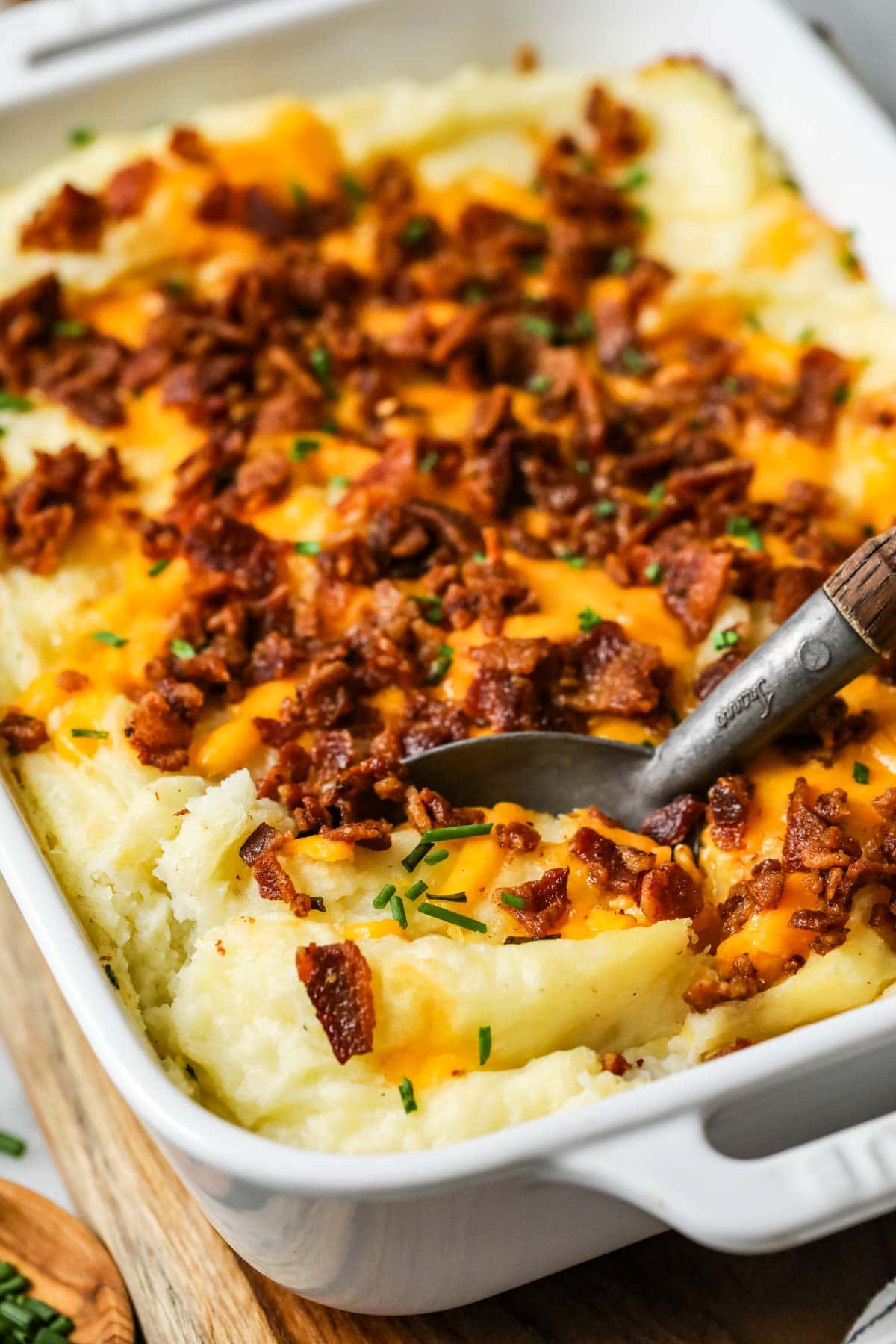 Spoon scooping a serving of mashed potato casserole out of a dish.