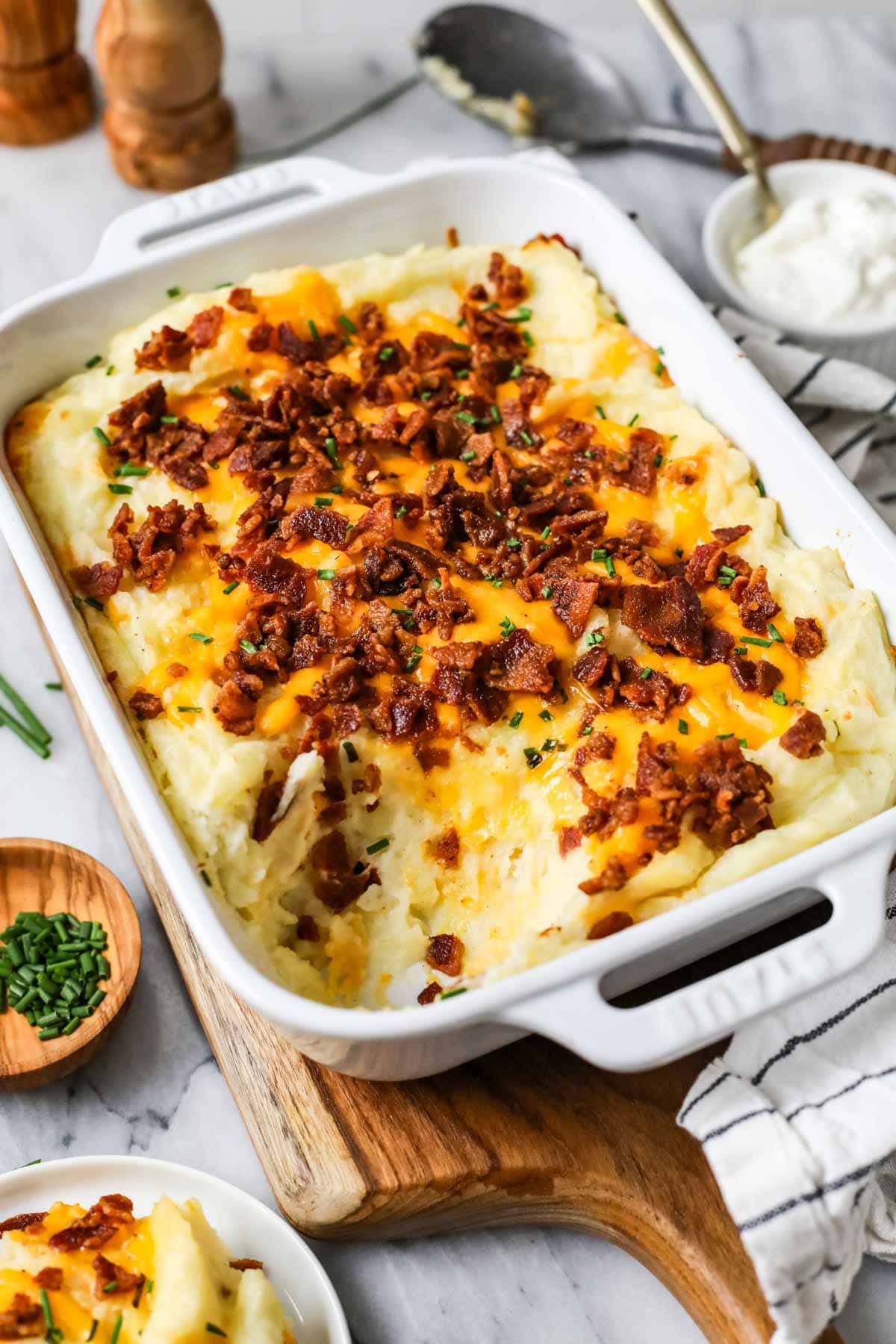 Dish of loaded mashed potato casserole with one serving missing.