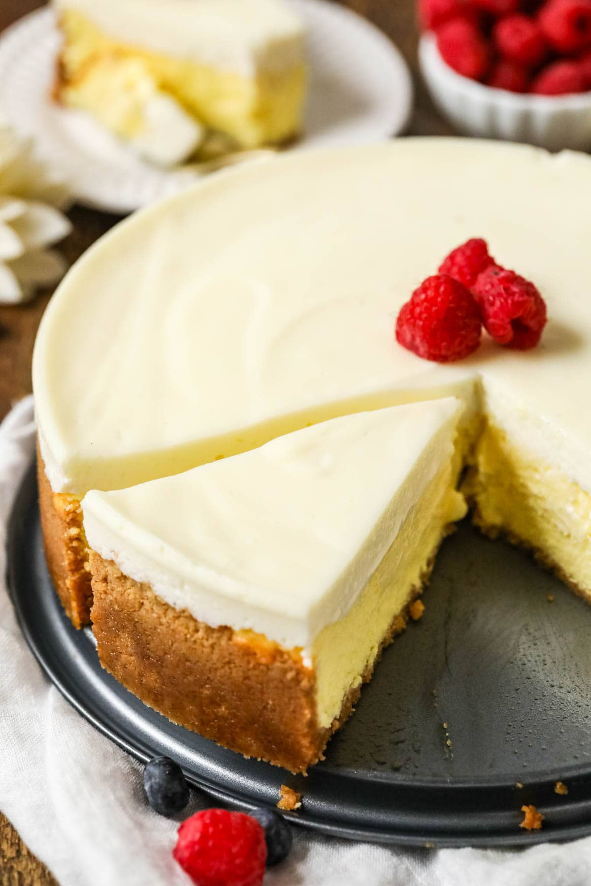 Slice of New York cheesecake sitting in the springform pan with the remaining cheesecake.