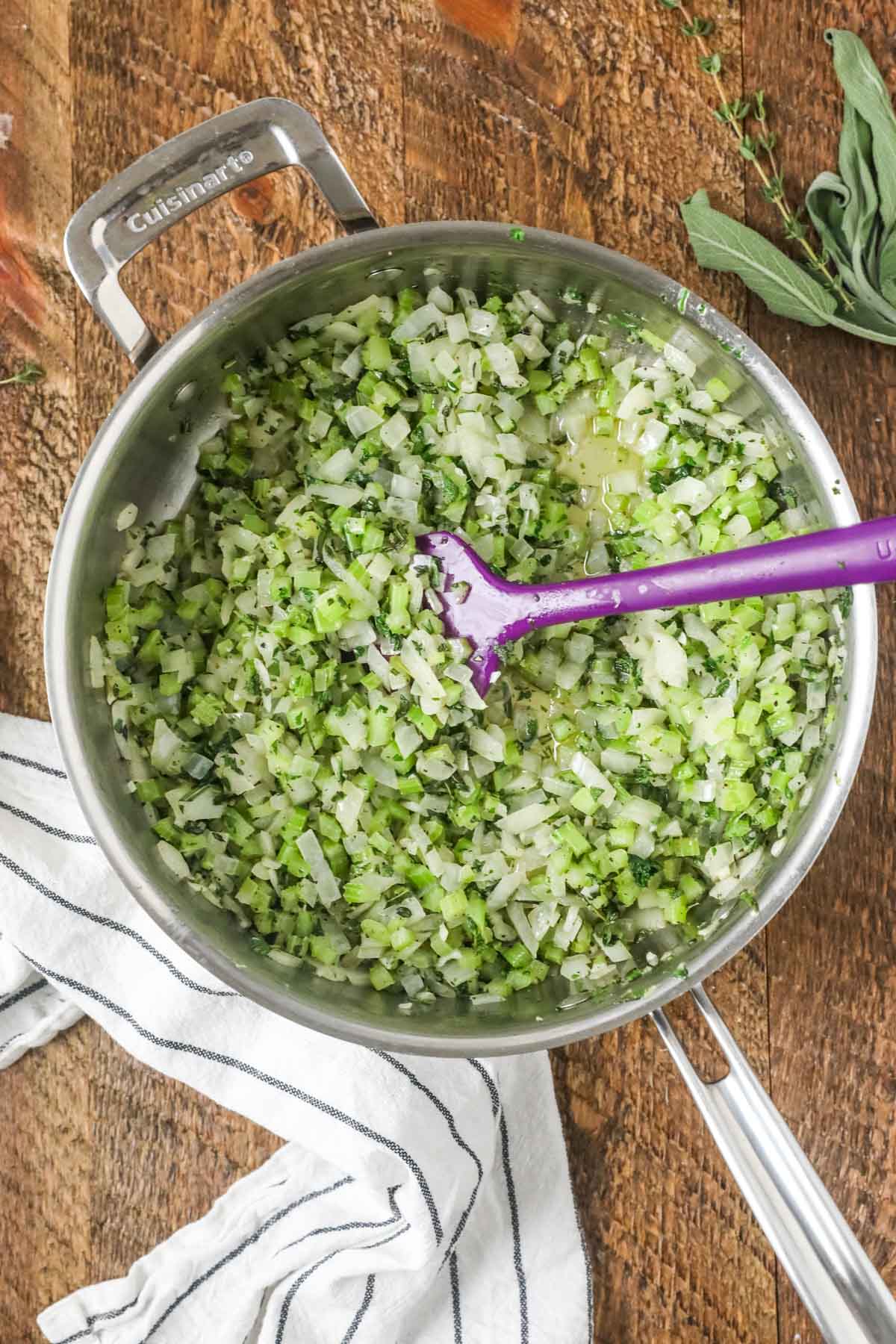 Overhead view of a saucepan of veggies and herbs.