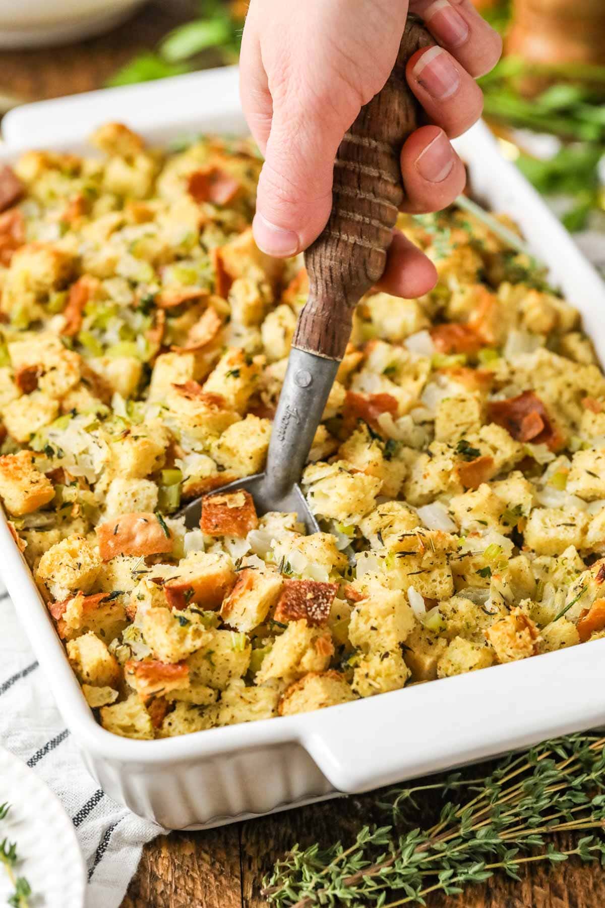 Spoon scooping out a serving of stuffing from a casserole dish.