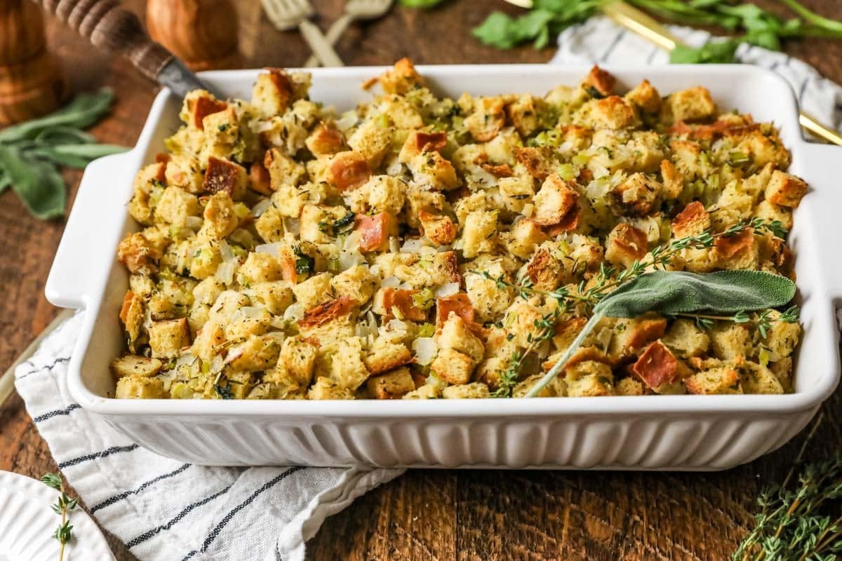 Pan of homemade stuffing topped with a fresh herb bundle.