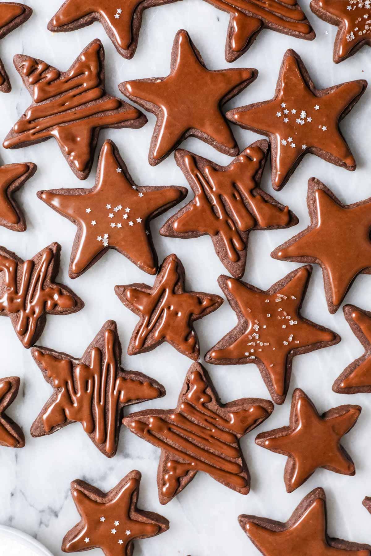 Overhead view of star shaped chocolate cookies topped with a shiny chocolate icing.