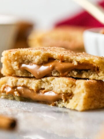 Two halves of cookie butter snickerdoodles stacked on top of each other with cookie butter spilling out of the centers.