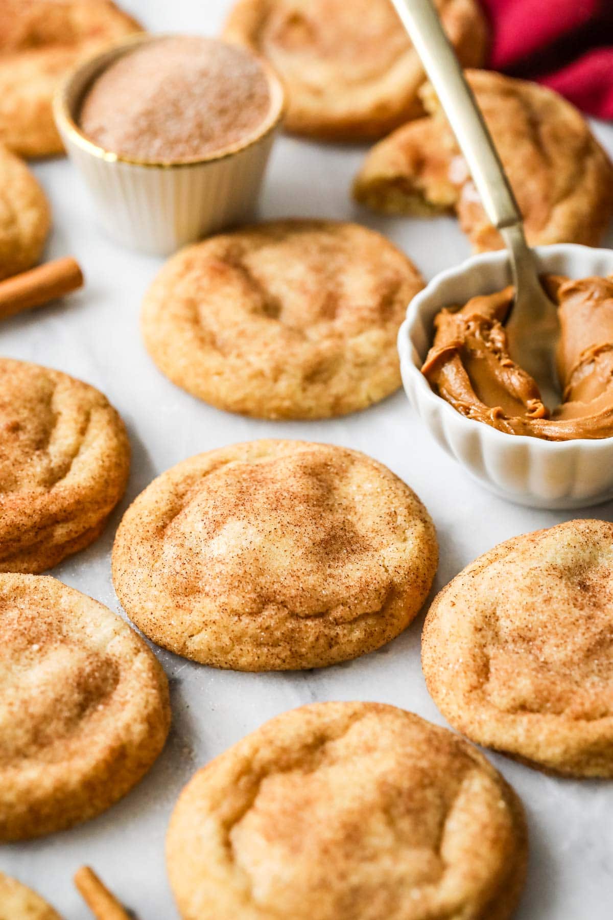 Cookie butter filled snickerdoodles among dishes of cinnamon sugar and cookie butter.