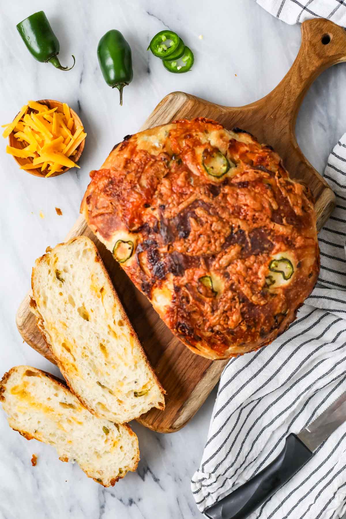 Overhead view of a loaf of sourdough cheddar jalapeno bread that's been cut into a few slices.