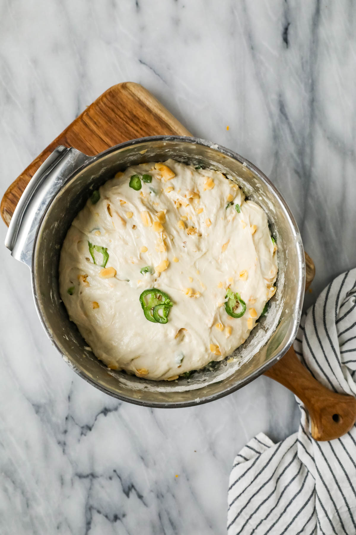 Overhead view of a bowl of dough made with cheddar and jalapenos after rising.