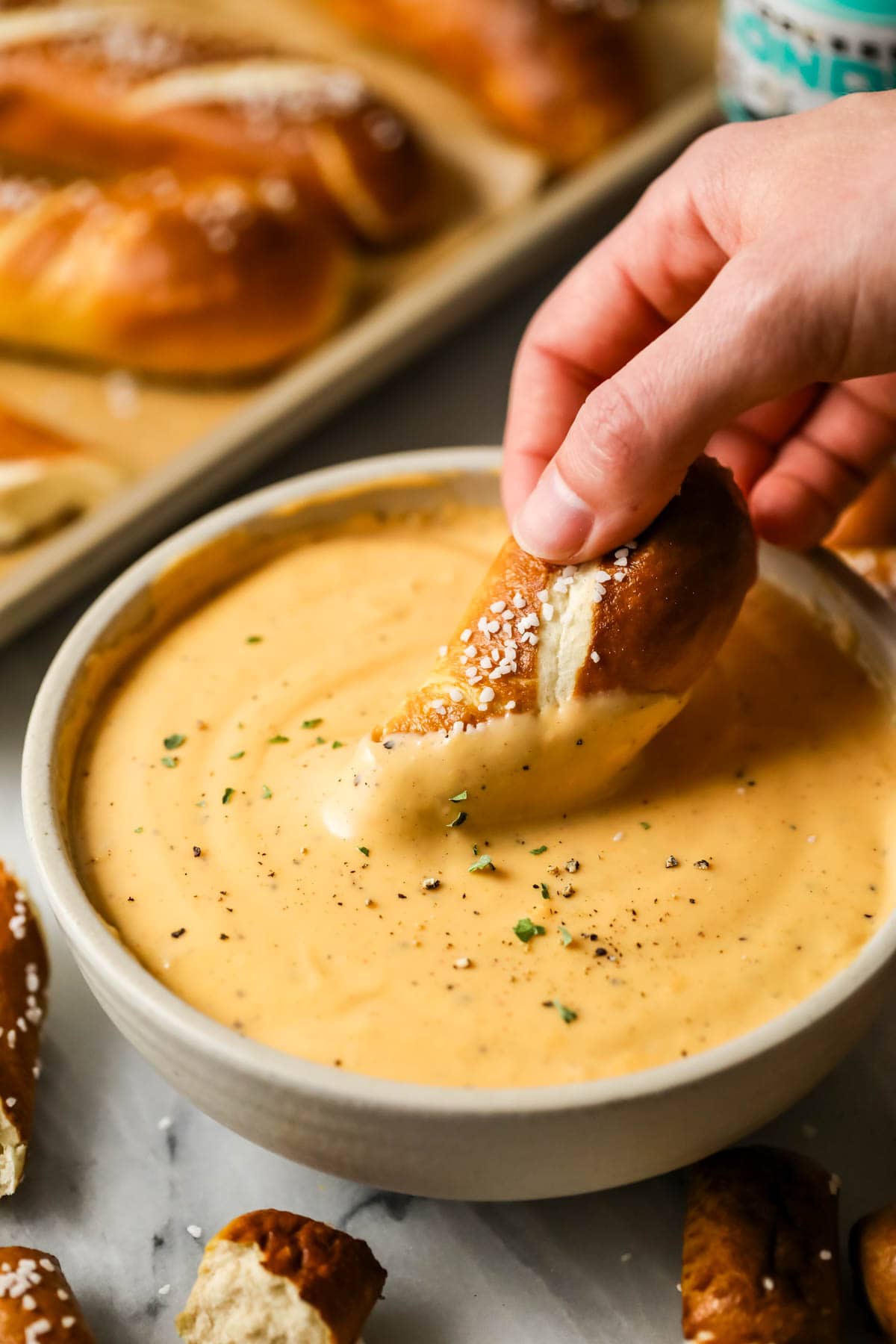 Pretzel being dipped into a bowl of beer cheese dip.