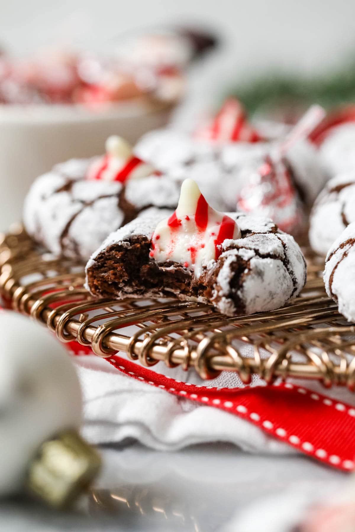 Bite missing from a Christmas kiss cookie made with chocolate cookie dough, powdered sugar, and candy cane kisses.