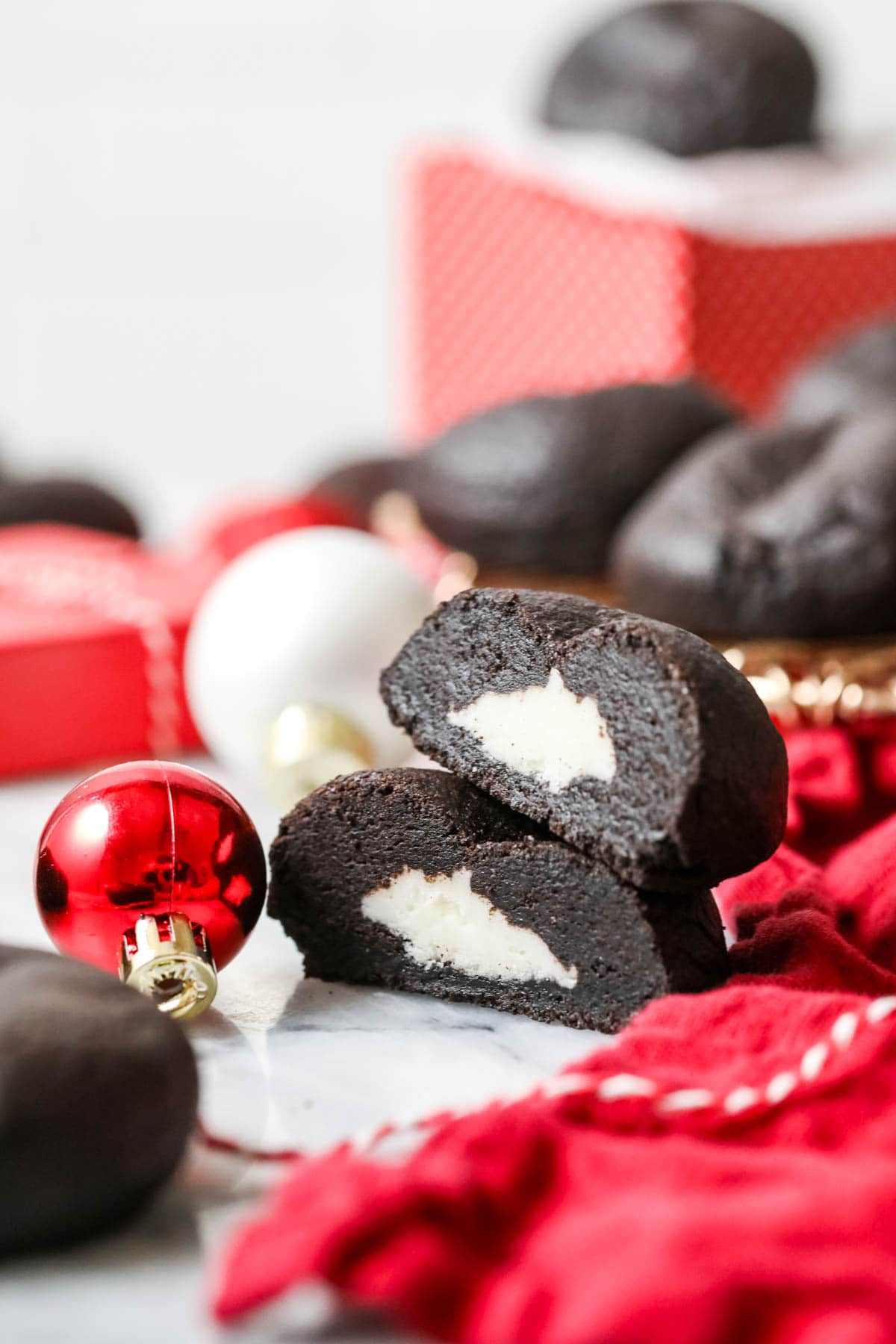 Two halves of a coal cookie made with black cocoa cookie dough and a buttercream frosting filling.