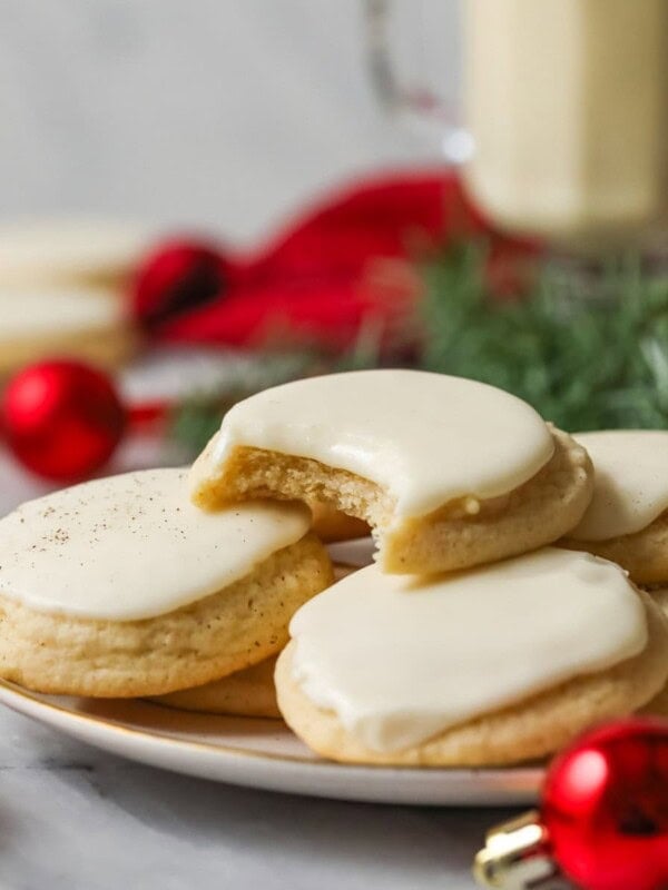 Plate of frosted eggnog cookies with a bite missing from the center cookie.