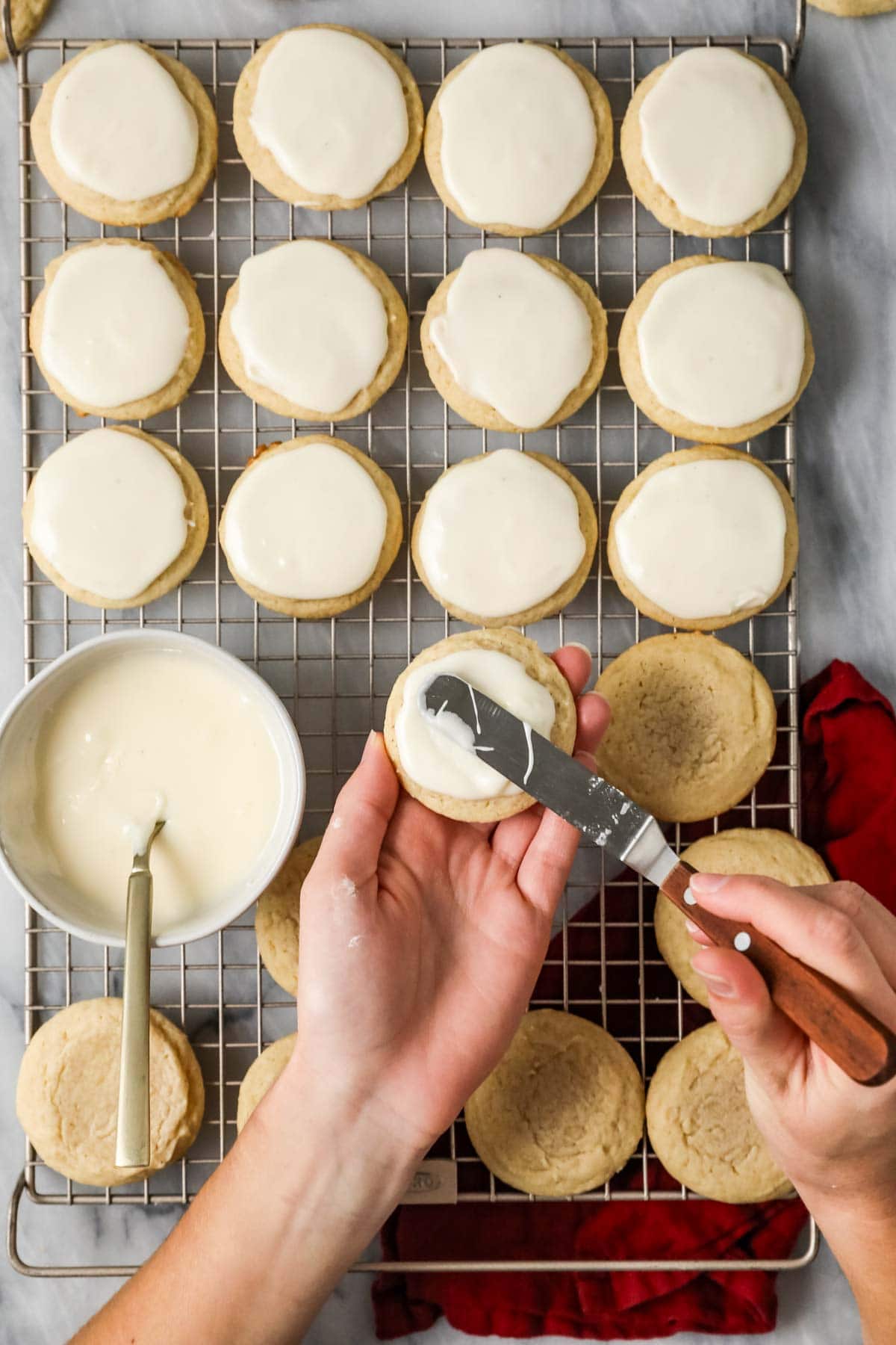 Overhead view of an eggnog frosting being spread onto cookies.