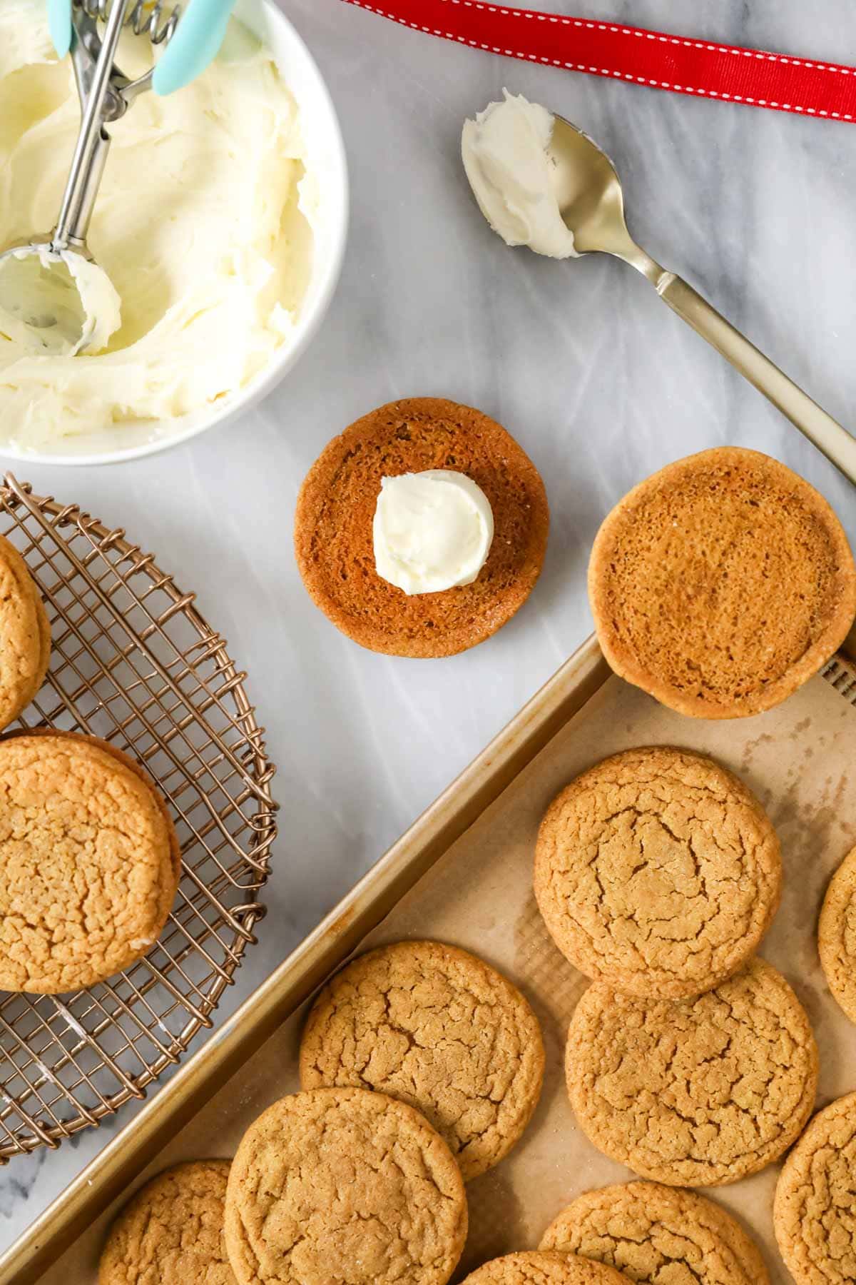 Dollop of frosting on a gingerbread cookie before adding the top cookie to make a sandwich.