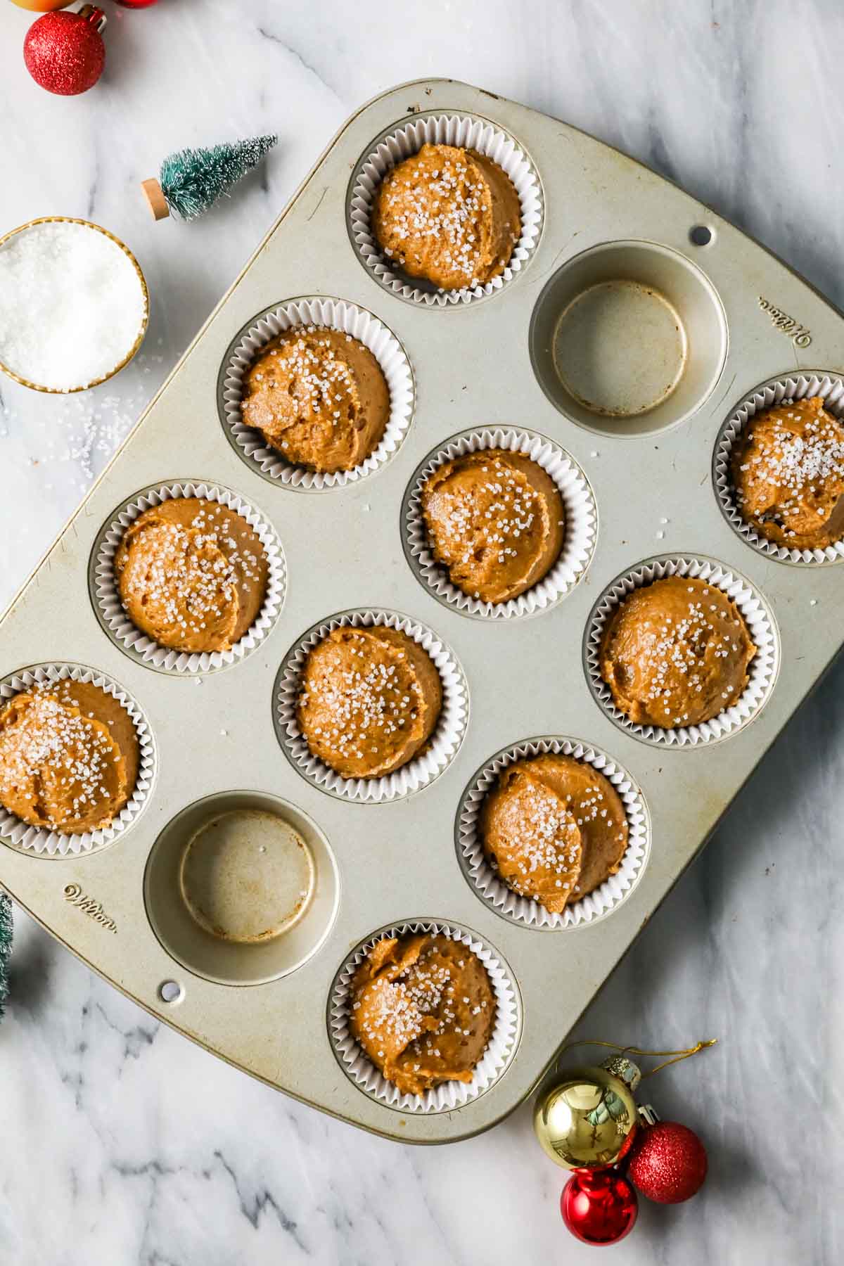 Overhead view of a muffin tin with gingerbread flavored muffin batter inside.