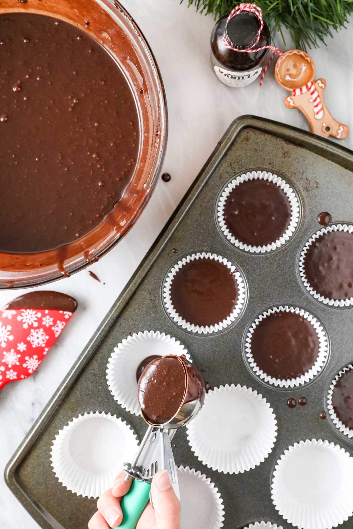 Dark chocolate cupcake batter being portioned into a lined muffin tin.