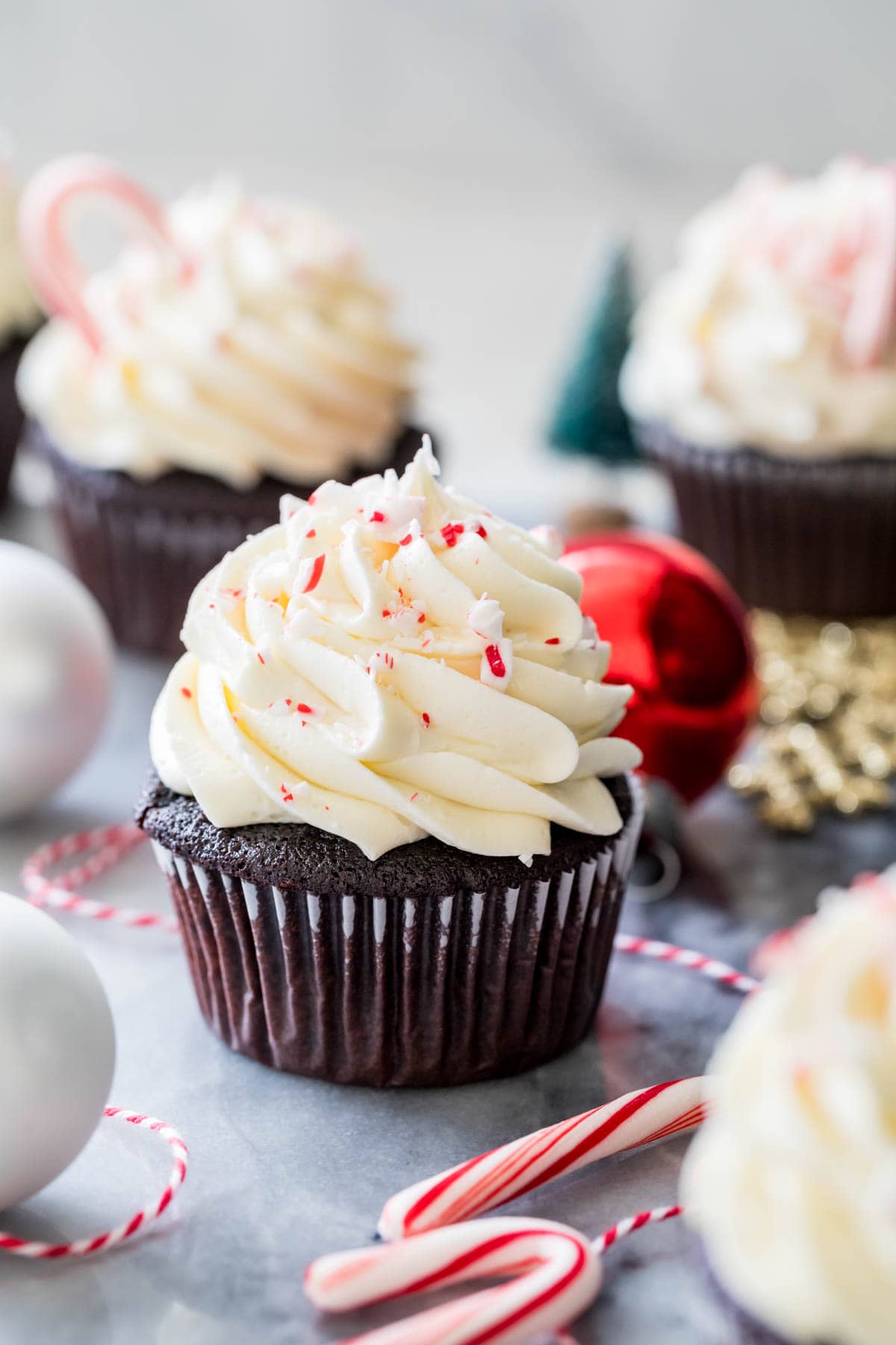 Dark chocolate cupcake topped with white chocolate peppermint buttercream and crushed candy cane pieces.