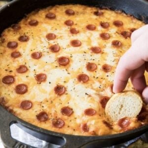 Bread being dipped into pepperoni pizza dip.