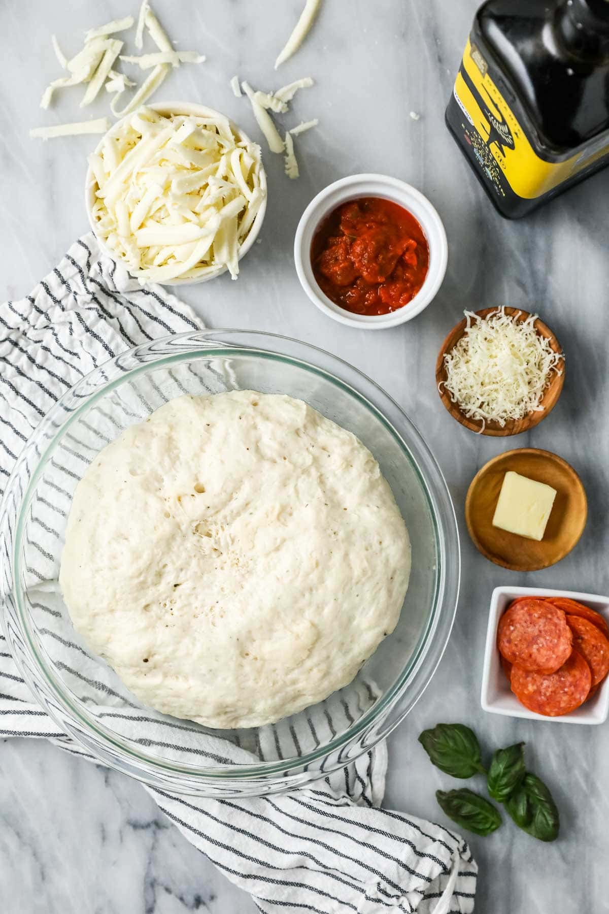 Overhead view of ingredients including pizza dough, cheese, sauce, and more.