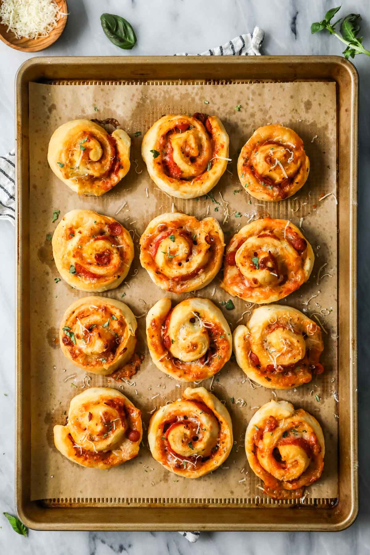 Overhead view of rows of swirled pizza rolls on a baking sheet.