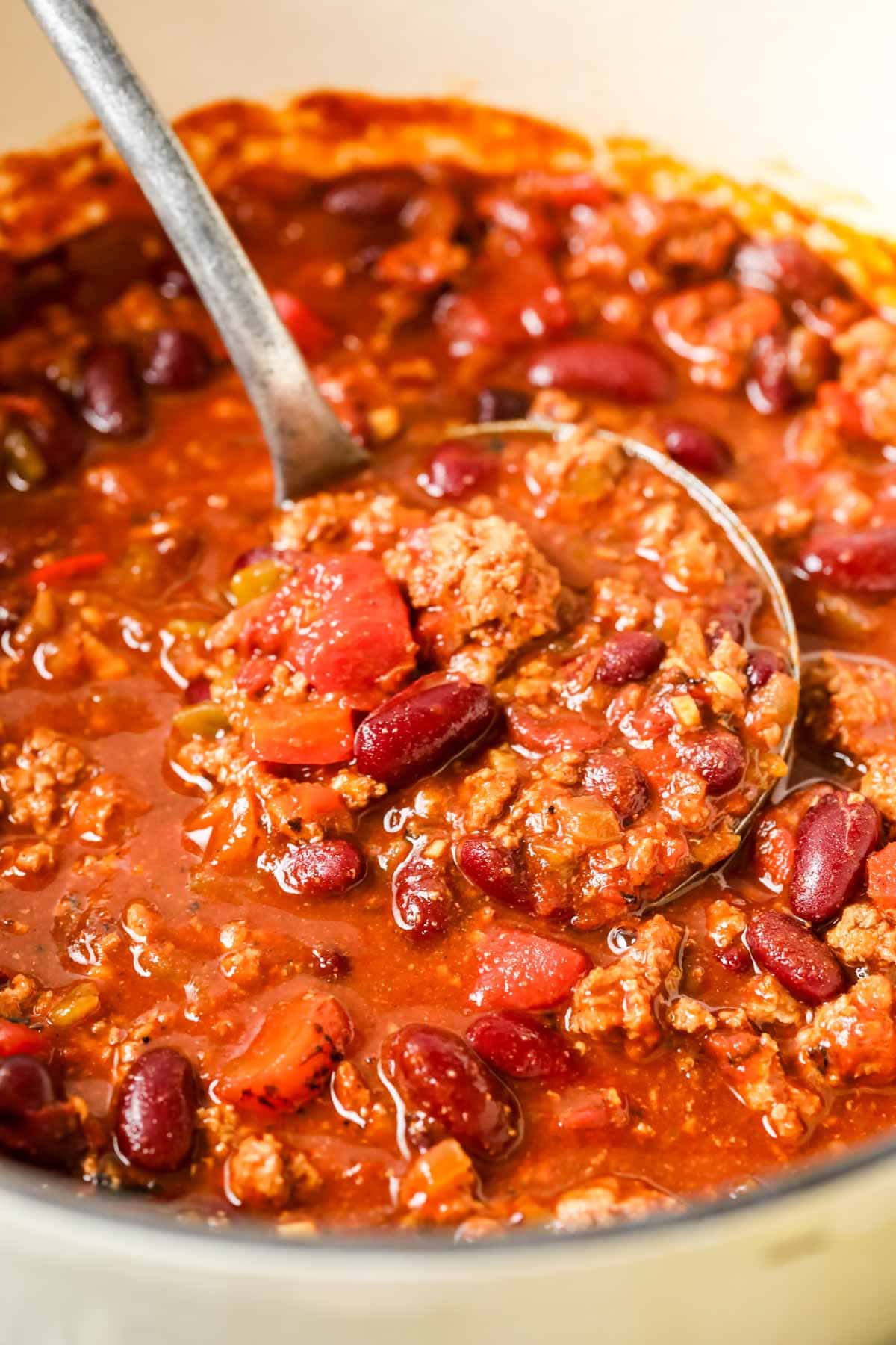 Close-up view of a ladle scooping a serving of chili made with ground turkey.