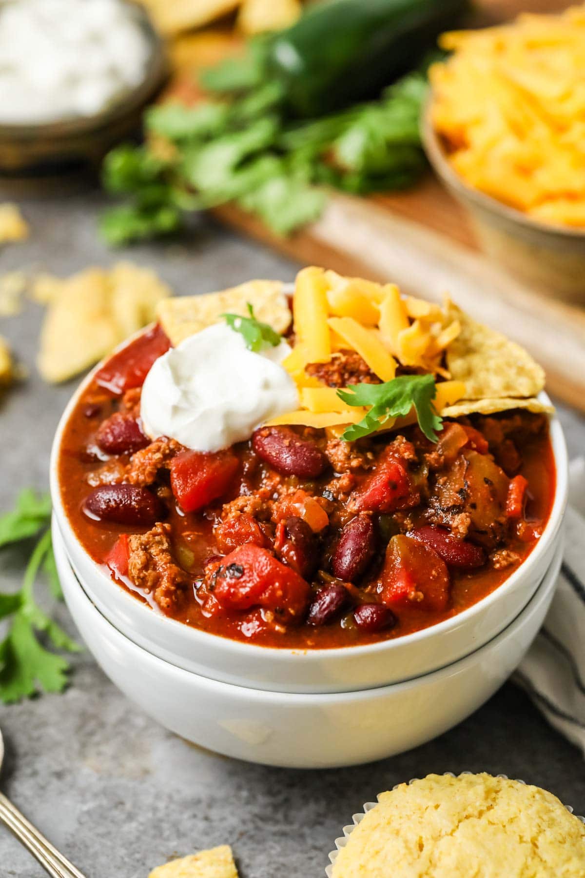 Bowl of turkey chili topped with sour cream, cheese, and tortilla chips.