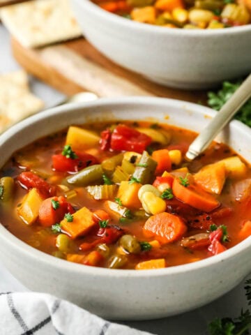 Bowl of vegetable soup made with carrots, potatoes, and more.