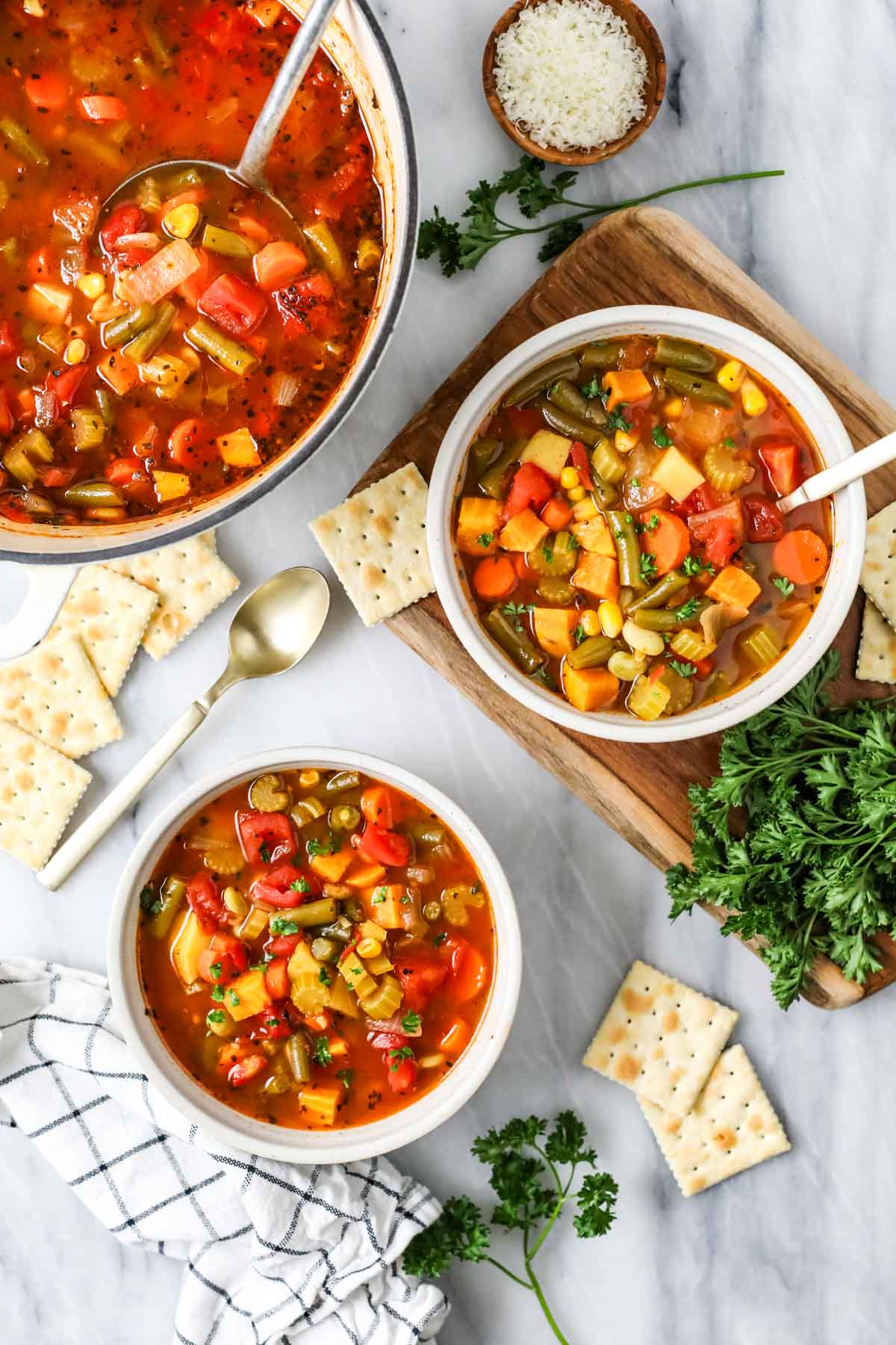 Overhead view of bowls of vegetable soup with crackers.