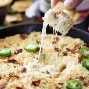 Cracker pulling cheese from a bacon jalapeno popper dip.