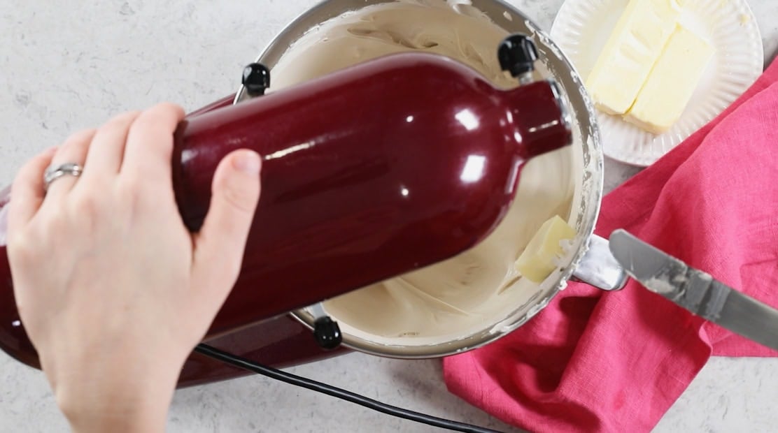 Overhead view of a mixer with butter being incorporated into a meringue.