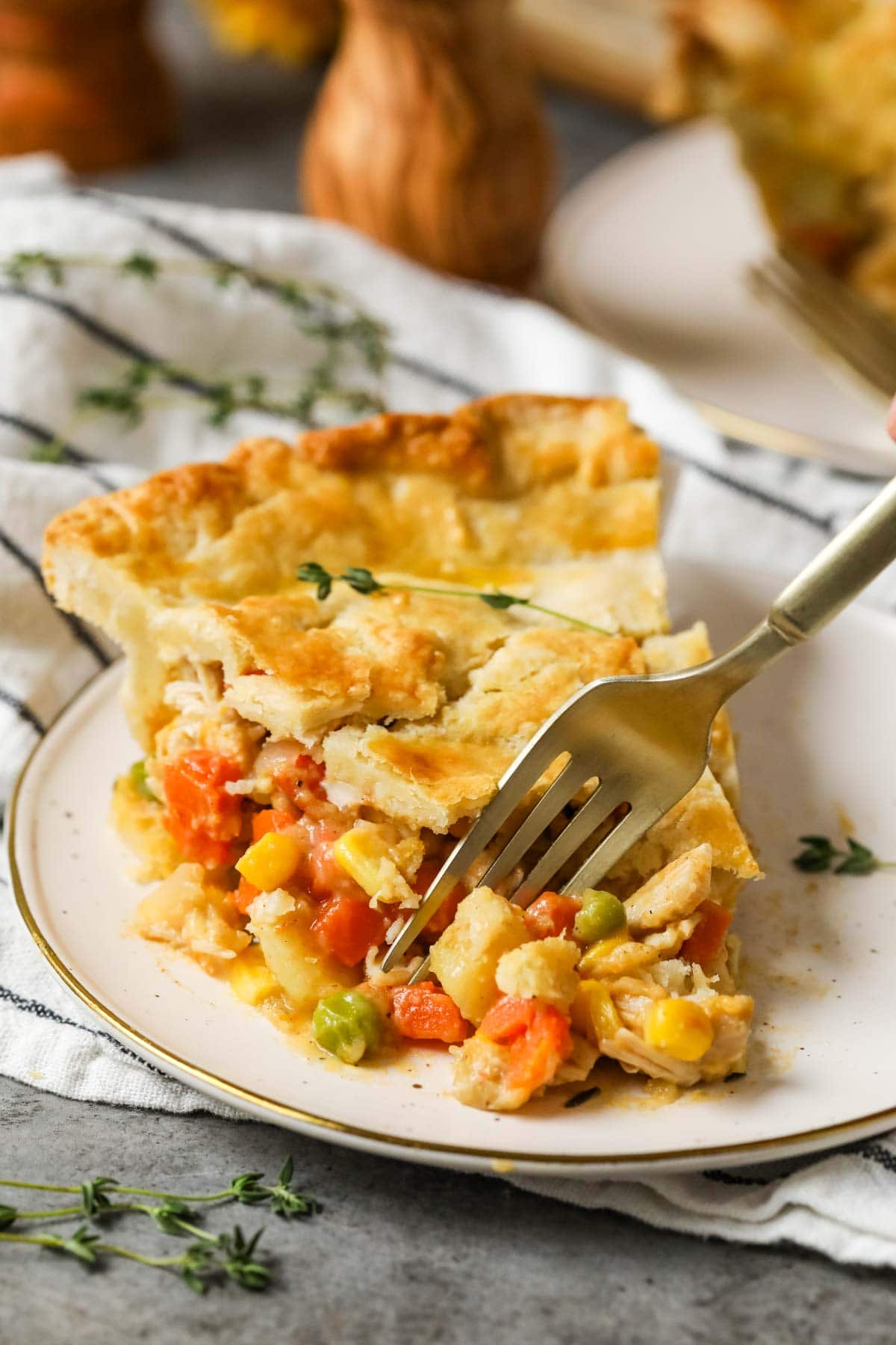 Slice of chicken pot pie on a plate with a fork grabbing a bite.