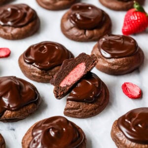 Chocolate covered strawberry cookies with the center cookie cut in half to show a strawberry frosting center.