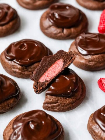 Chocolate covered strawberry cookies with the center cookie cut in half to show a strawberry frosting center.