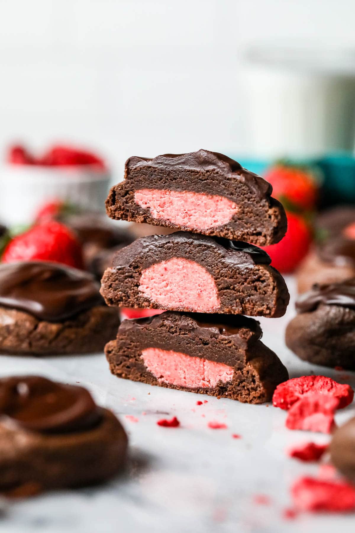 Three chocolate cookie halves stacked on top of each other to show their strawberry buttercream centers.