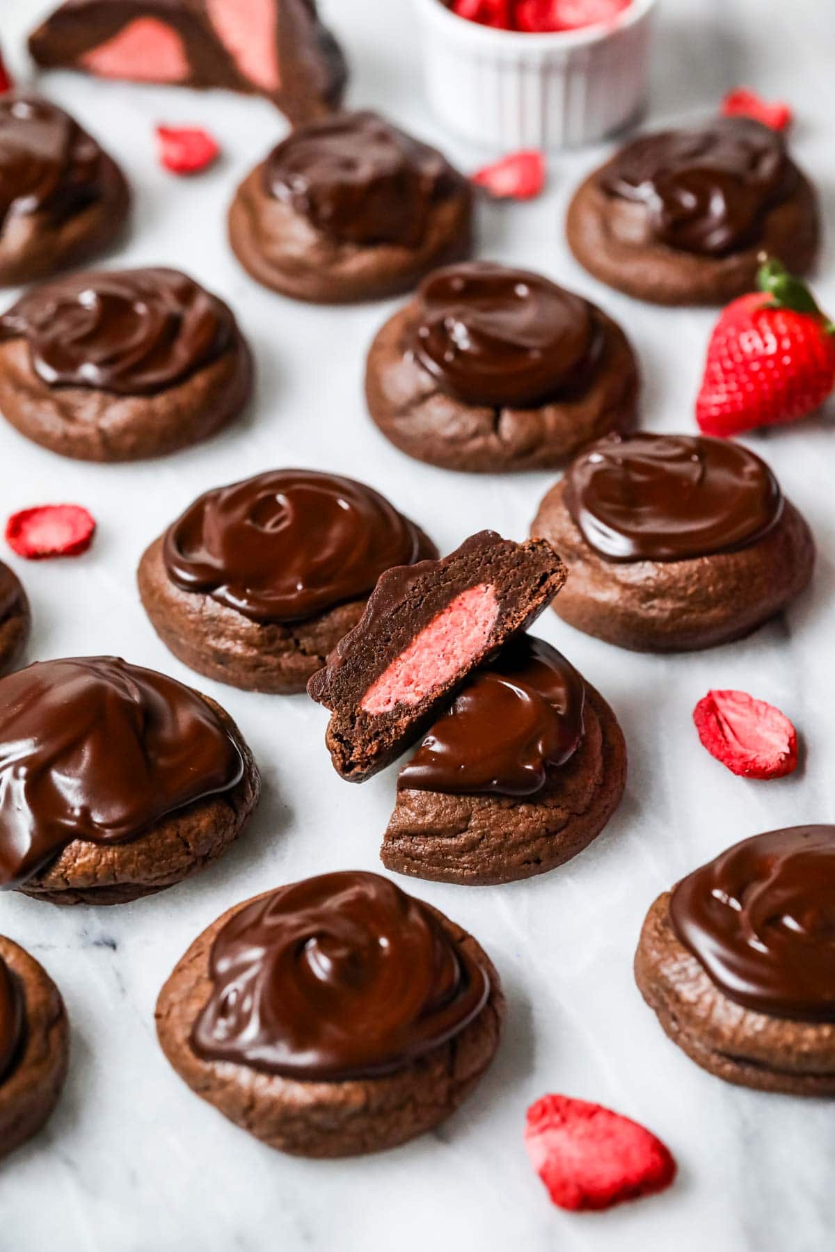 Chocolate covered strawberry cookies with the center cookie cut in half to show a strawberry frosting center.