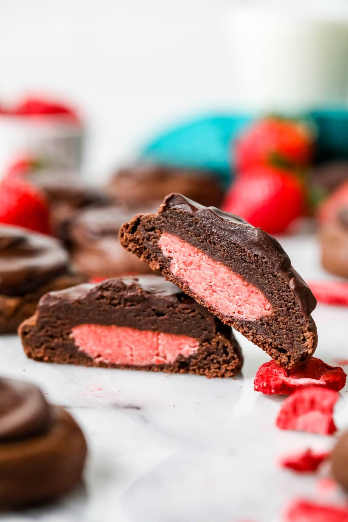 Two halves of a chocolate covered strawberry cookie stacked on top of each other.