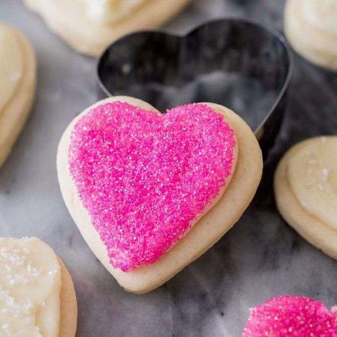 Heart shaped cream cheese sugar cookie topped with pink sprinkles.