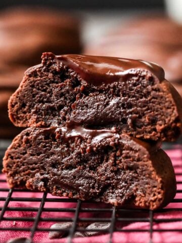 Two halves of a devil's food cookie stacked on top of each other to show a frosting center.