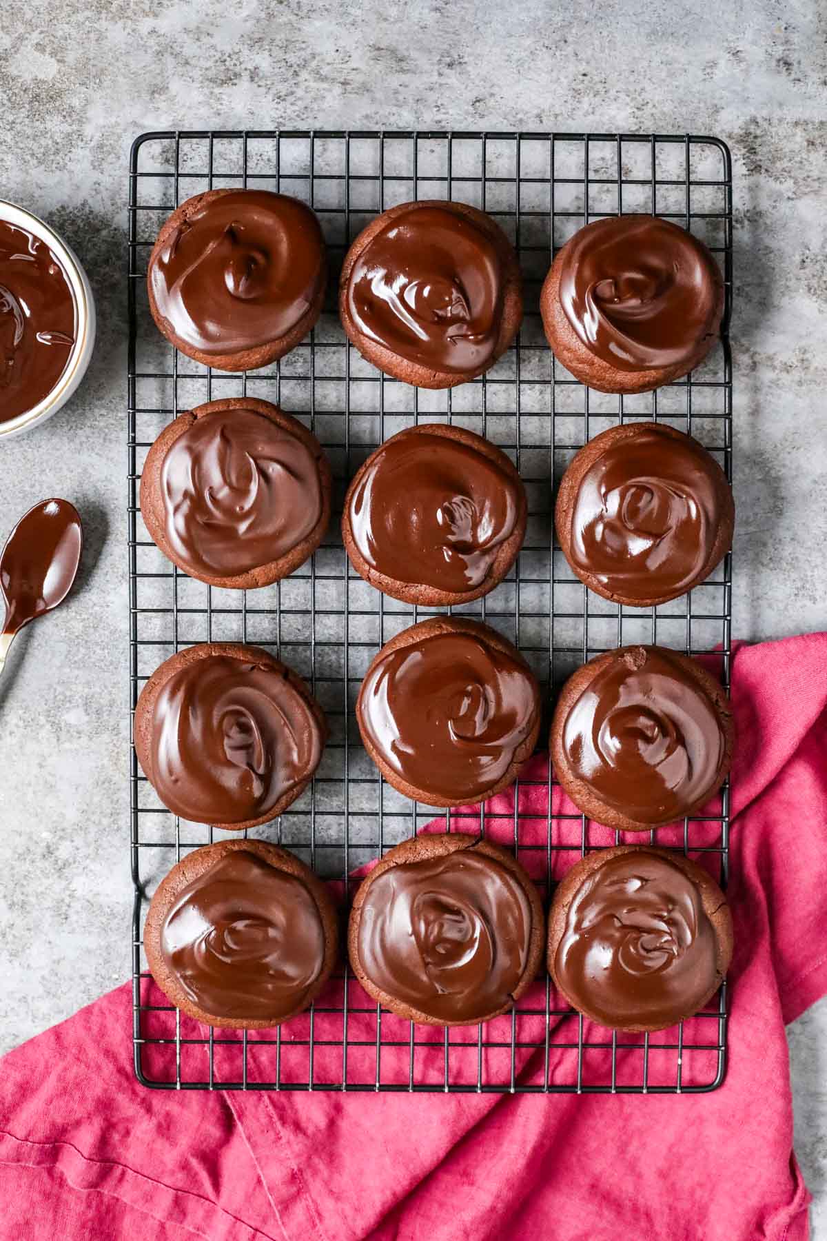 Overhead view of rows of devil's food cake cookies topped with chocolate ganache on a cooling rack.