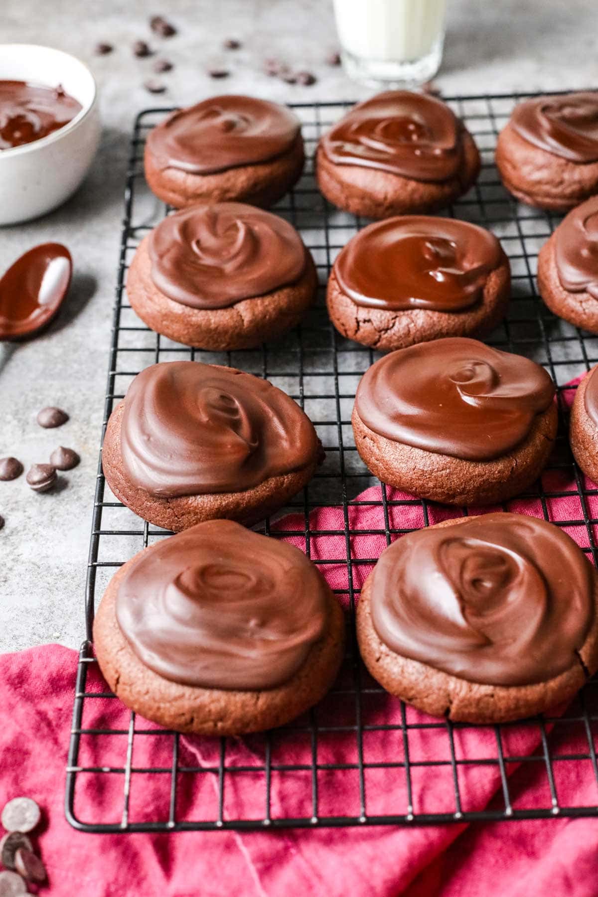 Rows of devil's food cake cookies topped with chocolate ganache on a cooling rack.