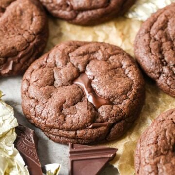 Close-up view of a double chocolate chunk cookie surrounded by more cookies and chocolate chunks.