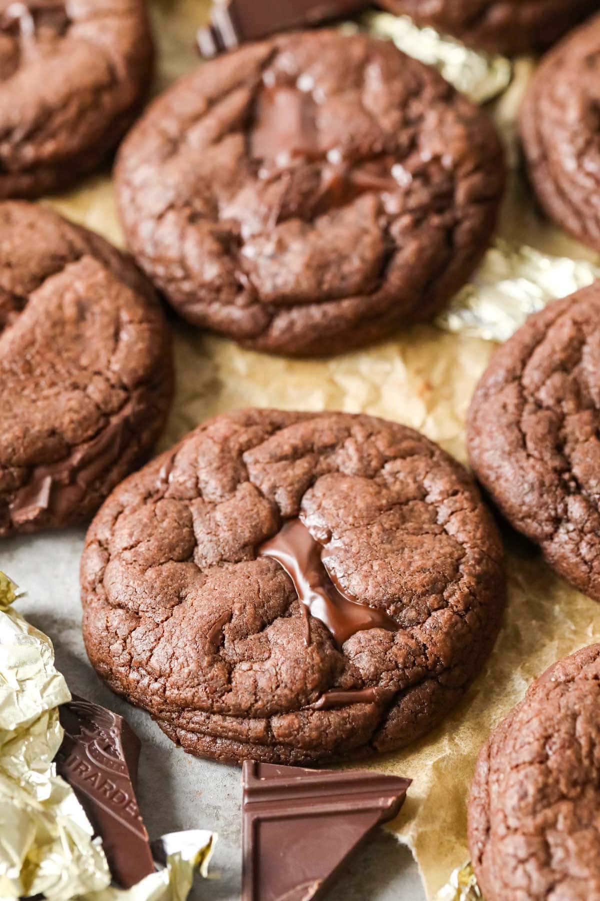 Close-up view of a double chocolate chunk cookie surrounded by more cookies and chocolate chunks.