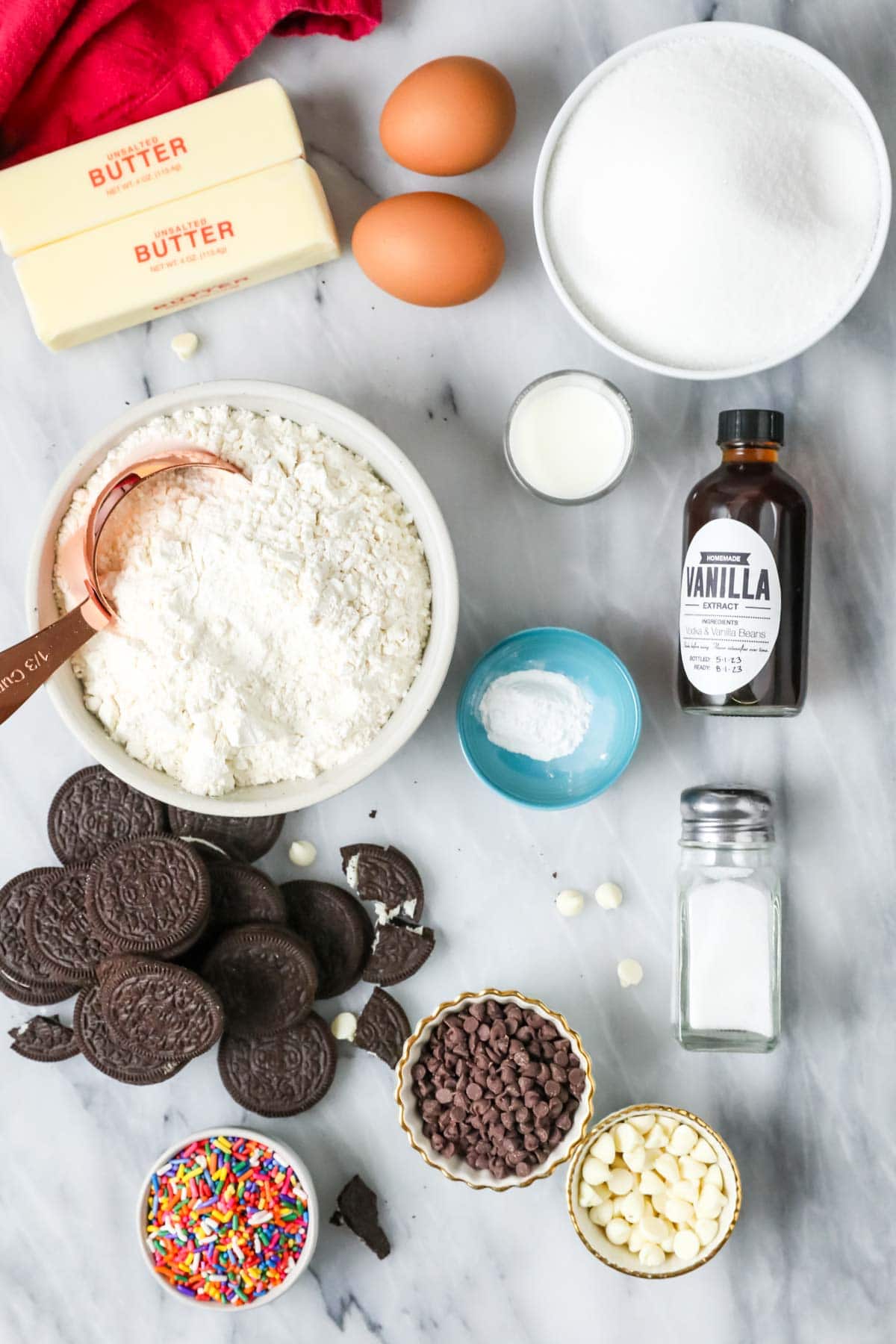 Overhead view of ingredients including flour, Oreos, sprinkles, white chocolate chips, and more.